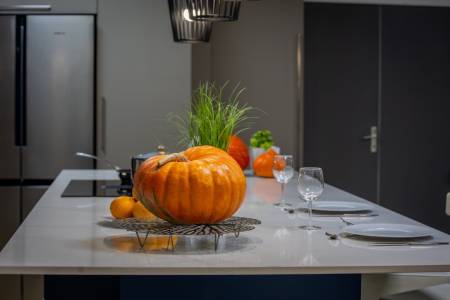 Cuisine design italienne avec immense îlot central en quartz Calacatta Gold, coin repas pour 4 à 6 personnes, réalisée par DB Design Cuisines en Gironde.