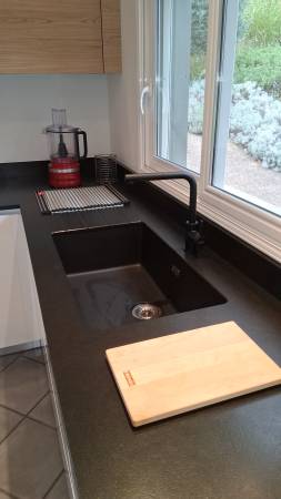 Évier par dessous, mitigeur noir mat et plan de travail en granit noir Zimbabwé : un trio d’élégance et de durabilité pour cette cuisine sur mesure sans poignées, installée près de Bordeaux.