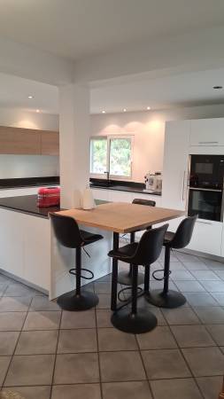 Ce coin snack sur mesure s’inscrit parfaitement dans une cuisine haut de gamme, avec une harmonie parfaite entre laque blanche, bois naturel et granit noir.