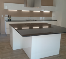 Création d un îlot central avec plaque de cuisson et hotte centrale ou le plan de travail en granit devient une véritable table